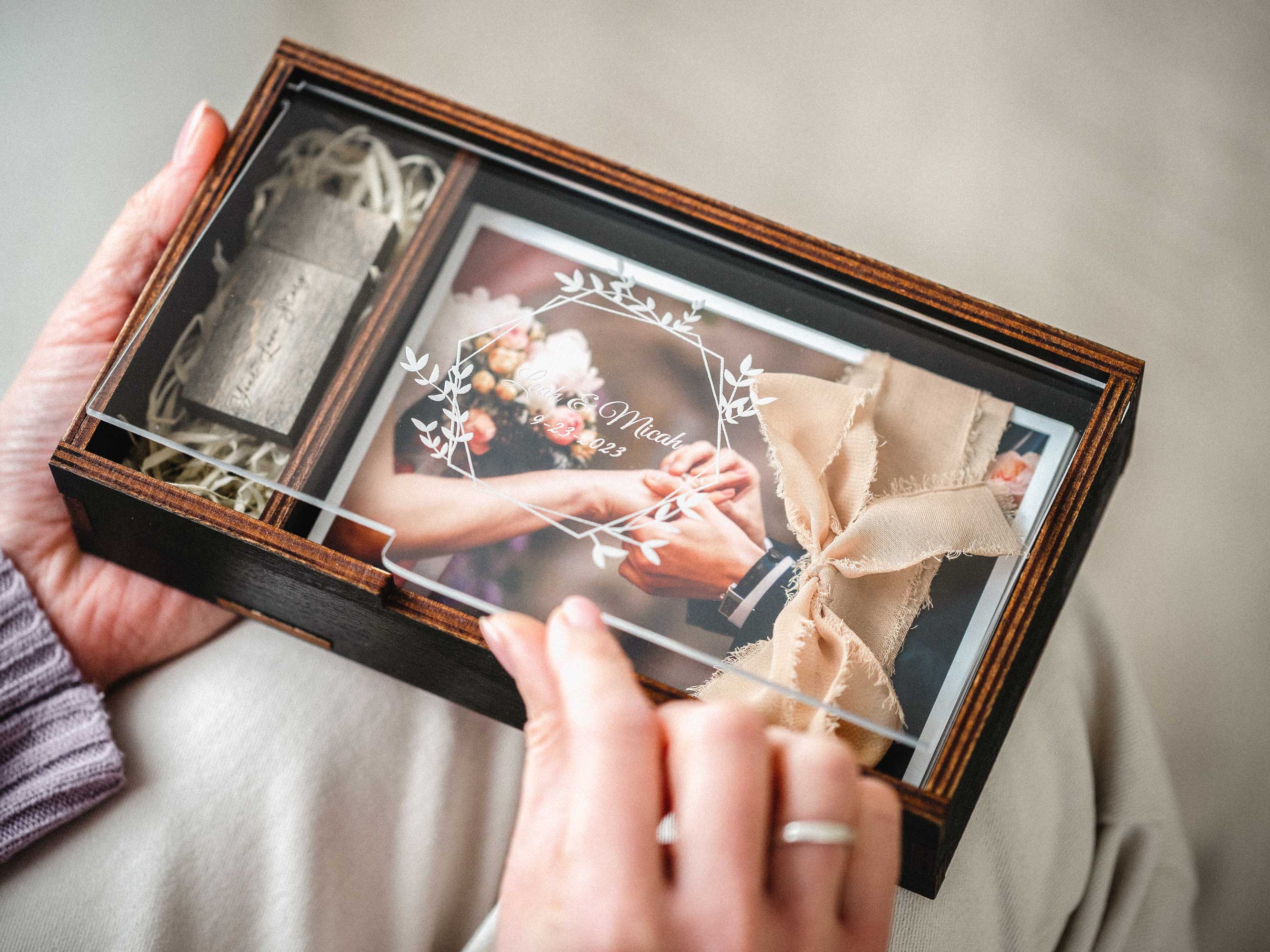 Black wedding photo box with USB compartment and tied photo prints in hands