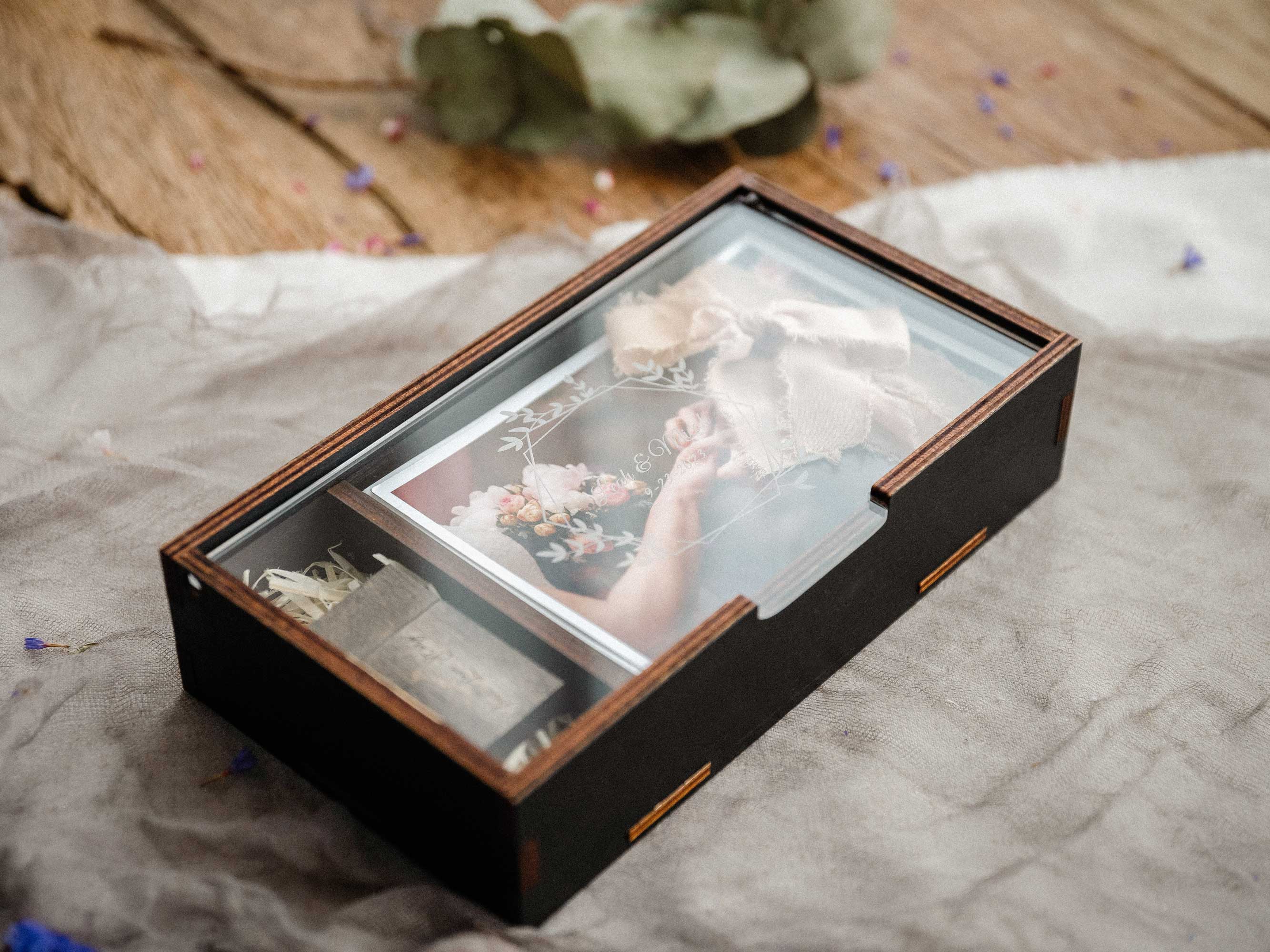 Black wooden photo box with personalized acrylic lid closed on fabric background