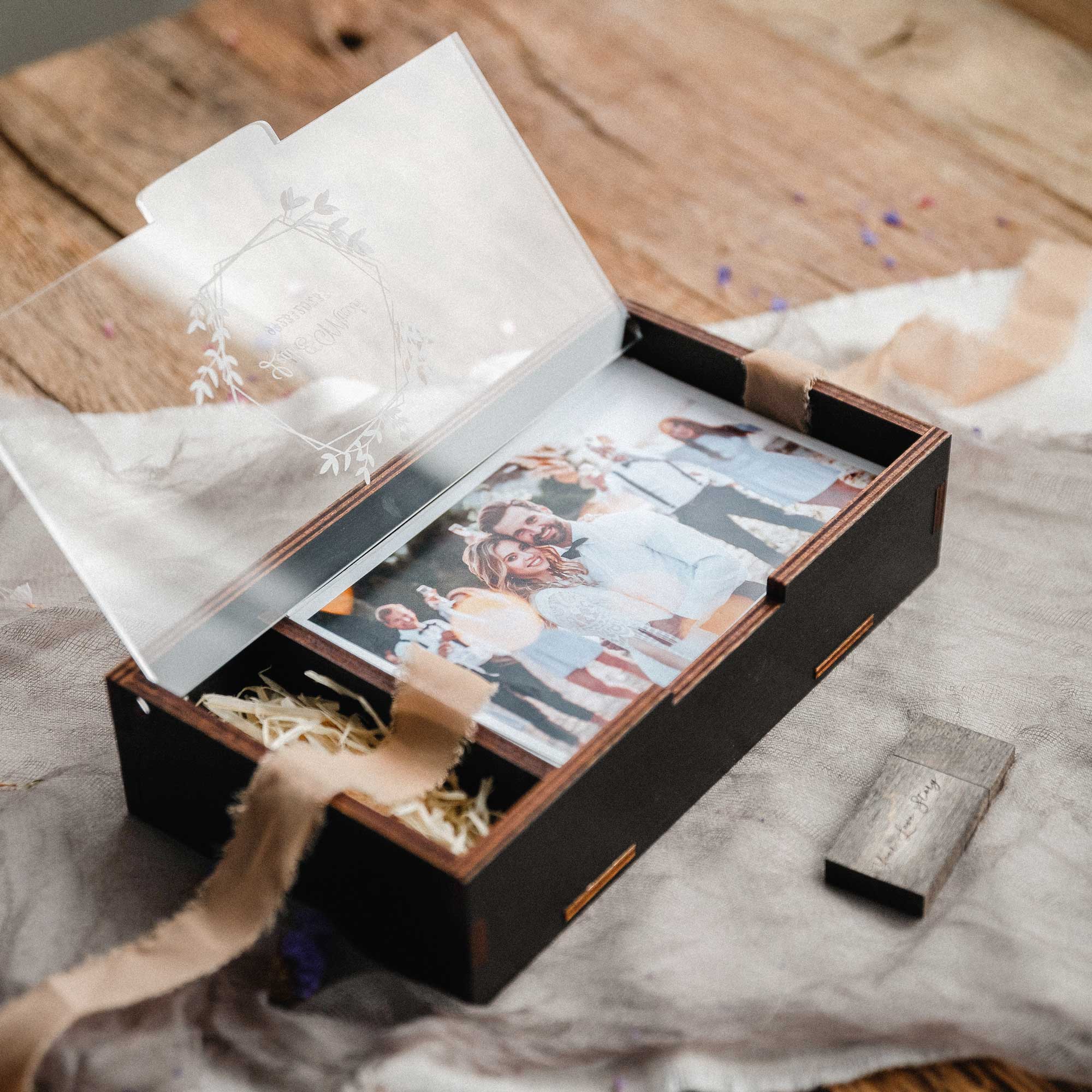 Open black wedding photo box with acrylic lid, wooden USB, and printed photos