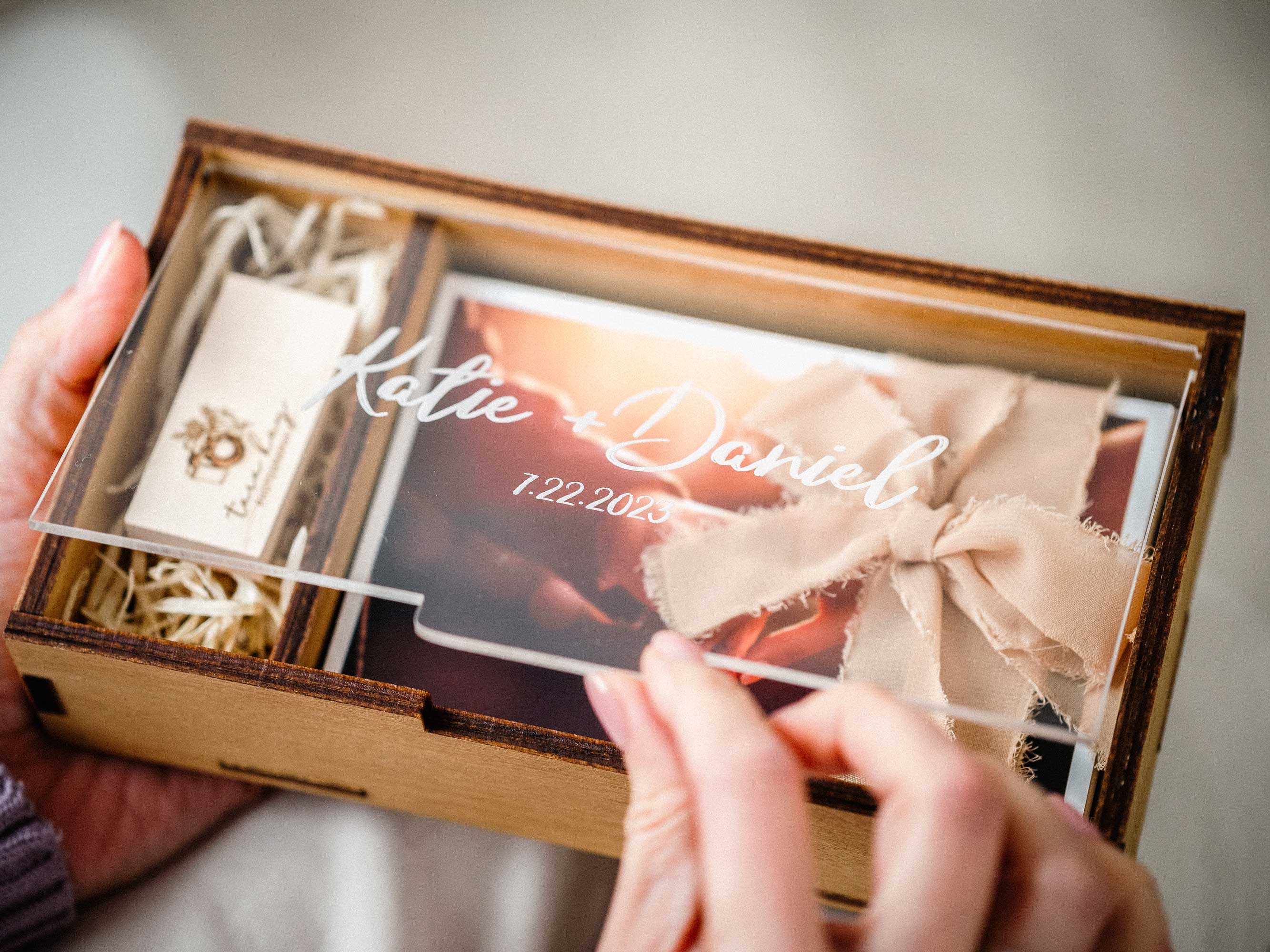 Gold Oak wedding photo box with USB compartment and tied photo prints in hands