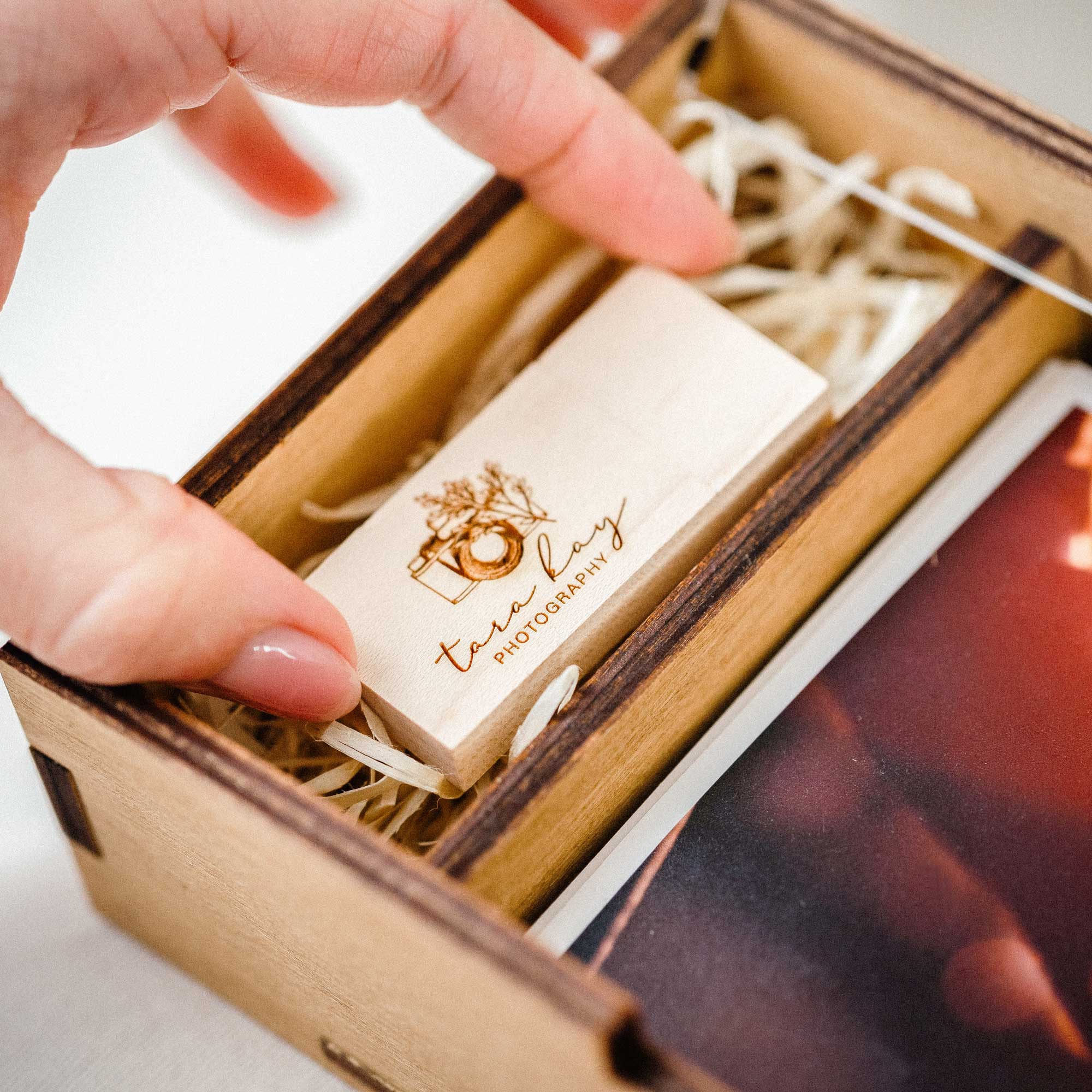 Wooden USB flash drive inside Gold Oak wedding photo box close-up