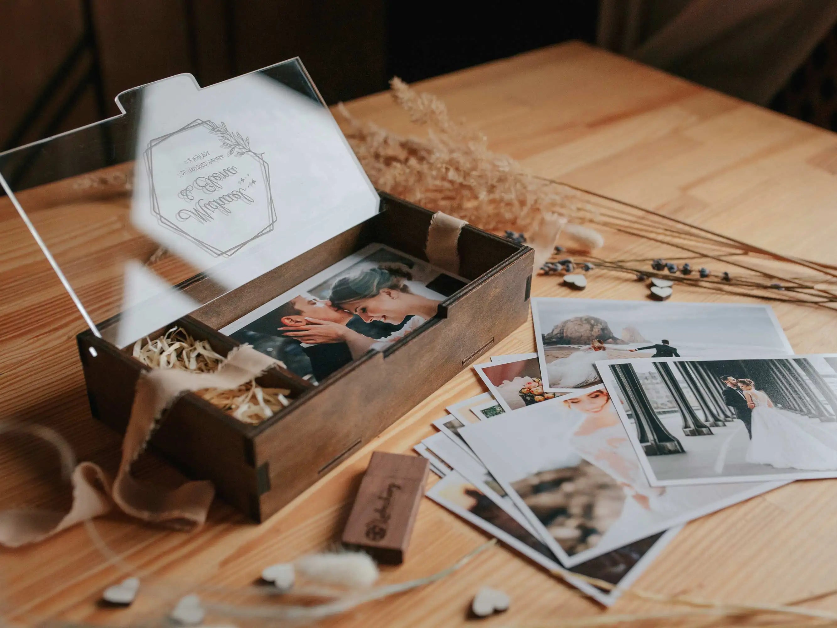 Wooden wedding photo box with personalized acrylic lid, wooden USB flash drive, and printed photos on a wooden table