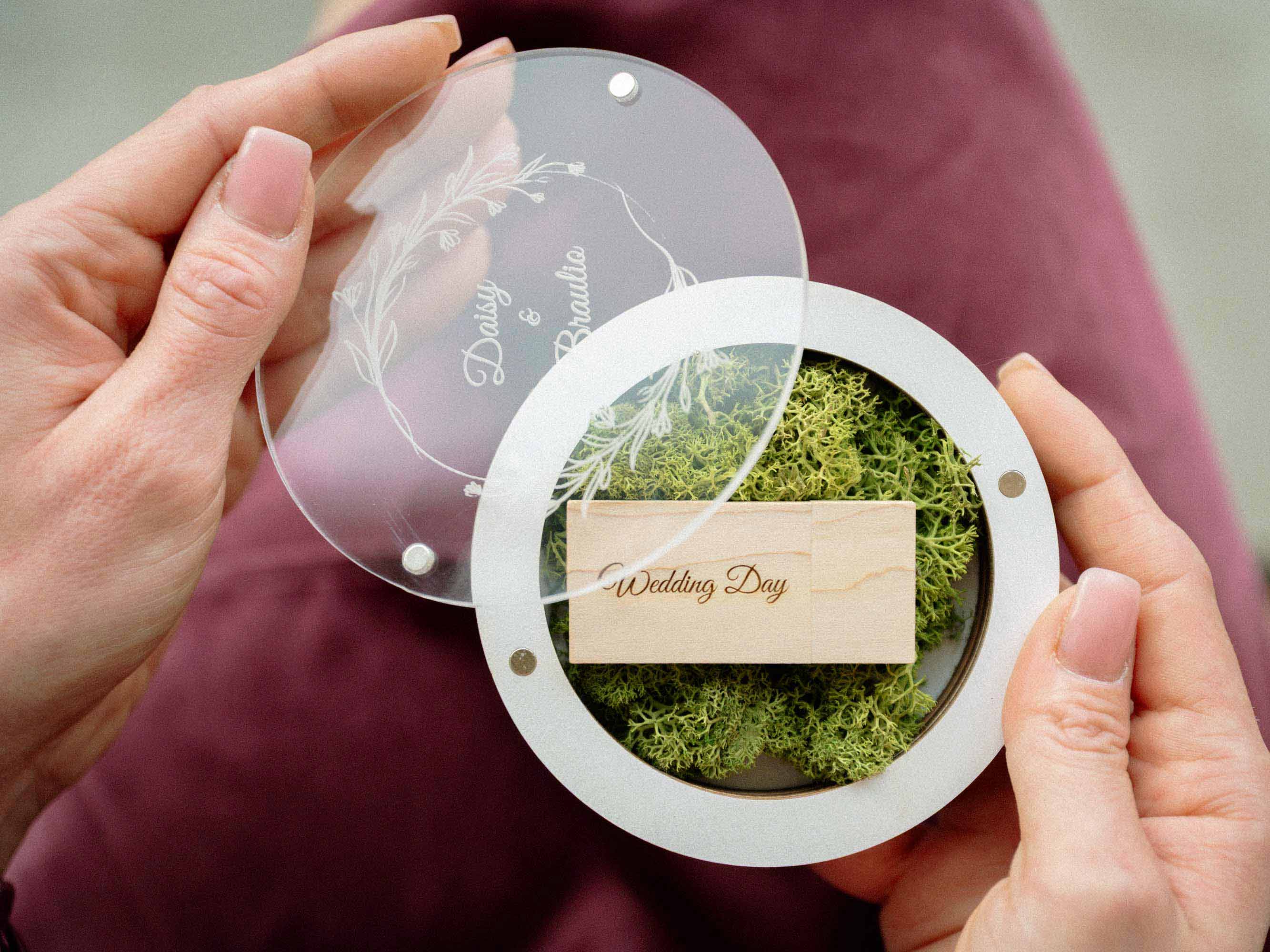Open white wedding USB box with acrylic lid and light wooden flash drive in hands