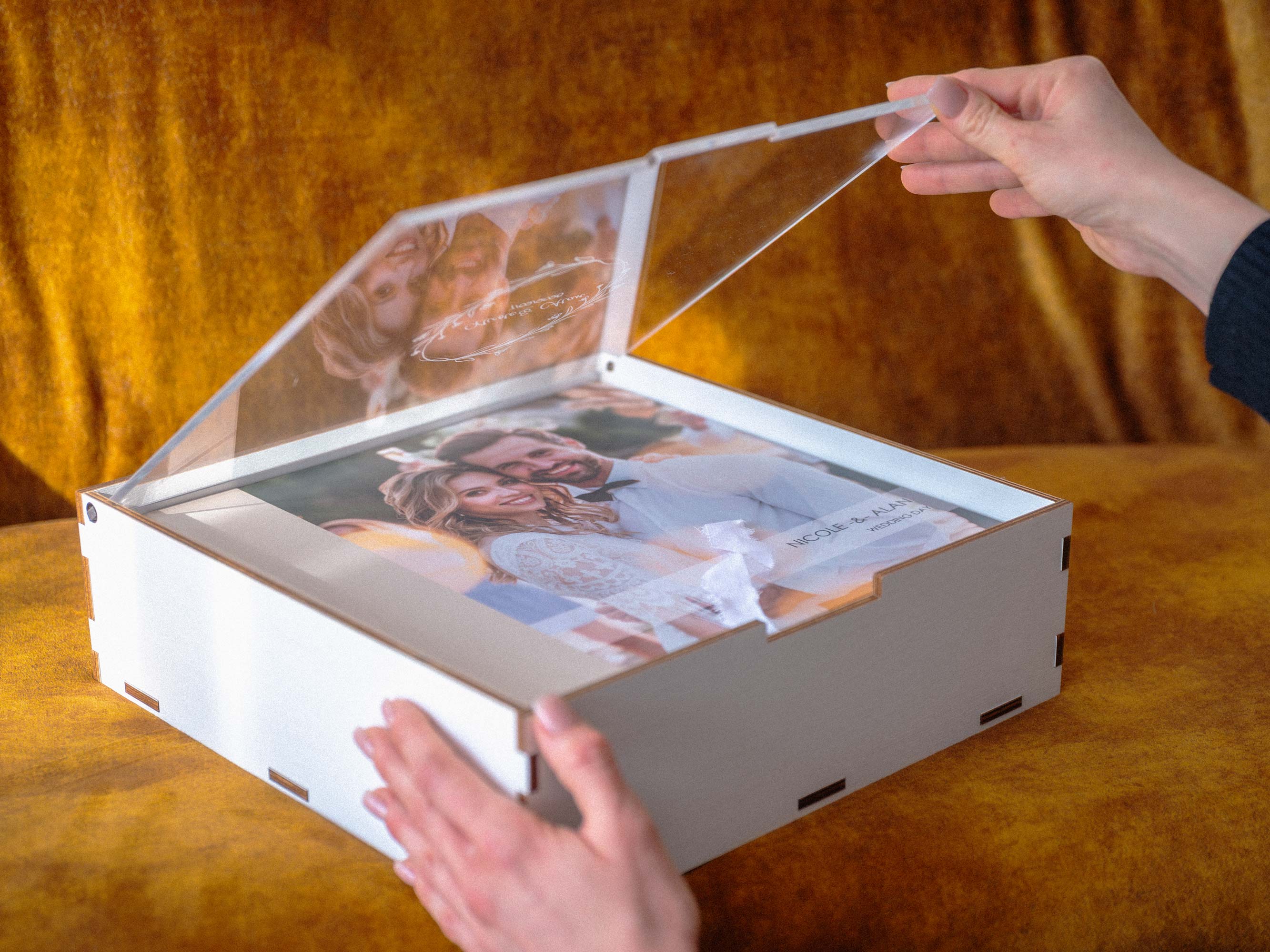 White wedding album box with clear acrylic lid being opened by hands