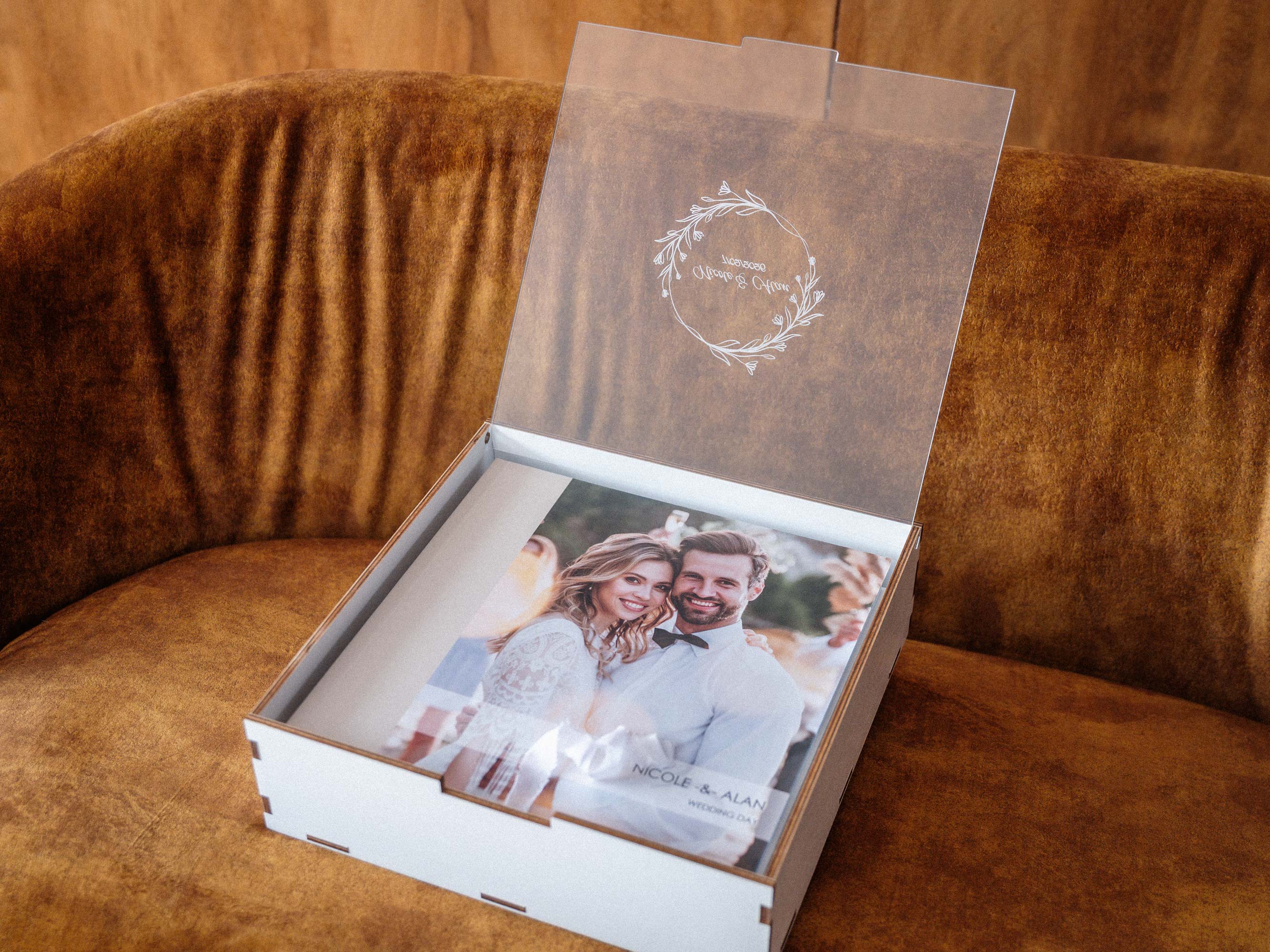 Personalized white wooden box for 10x10 in photo album with acrylic lid open on sofa