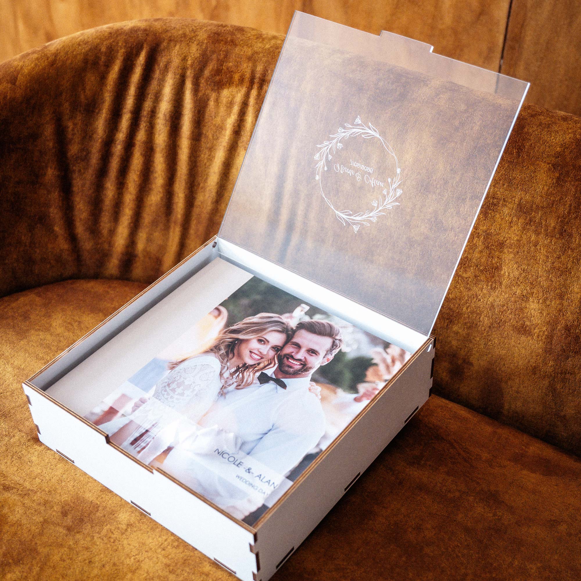 White wedding album box with personalized acrylic lid displayed open on chair