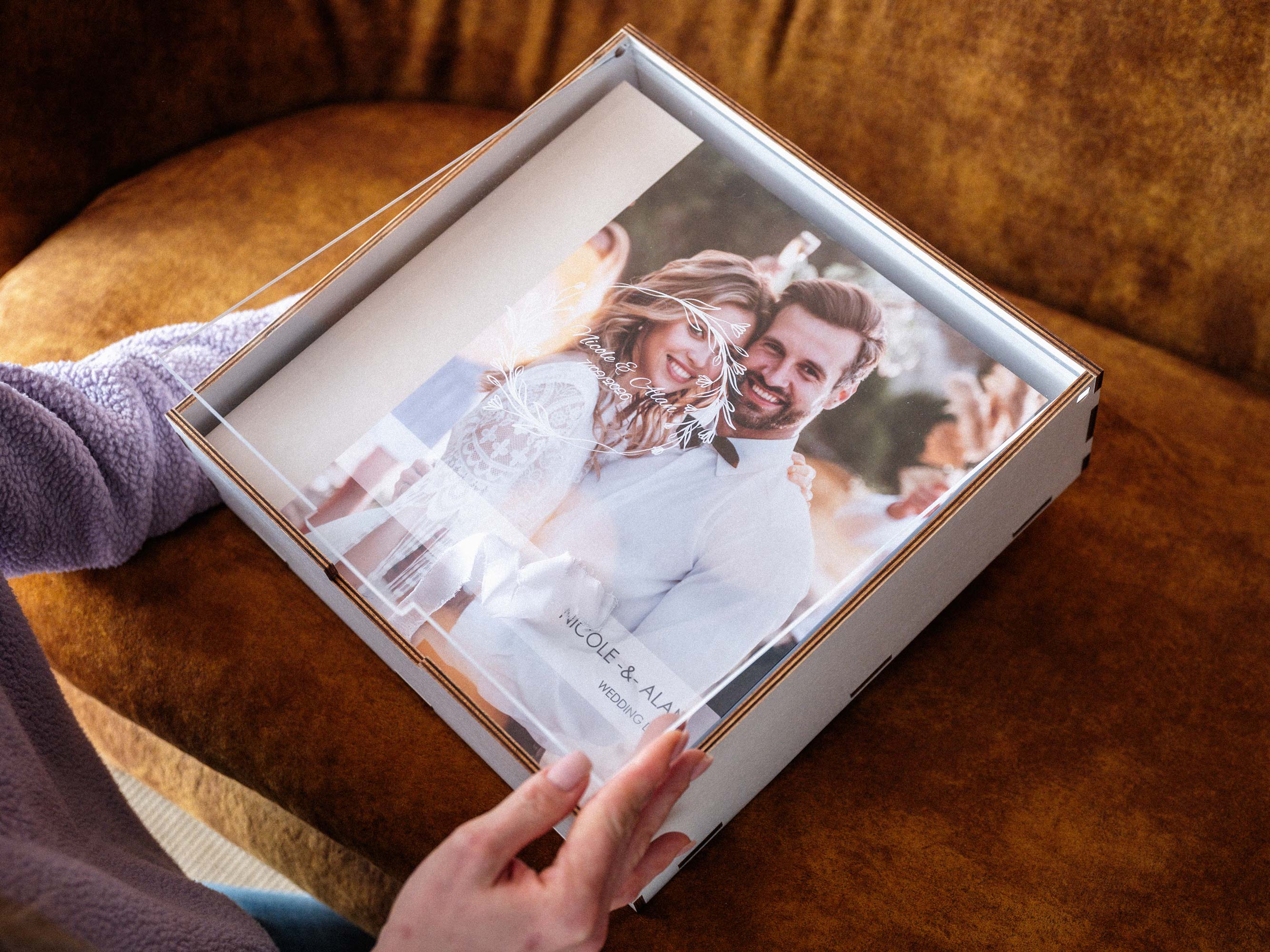 White photo album storage box with acrylic lid held in hands, wedding album inside