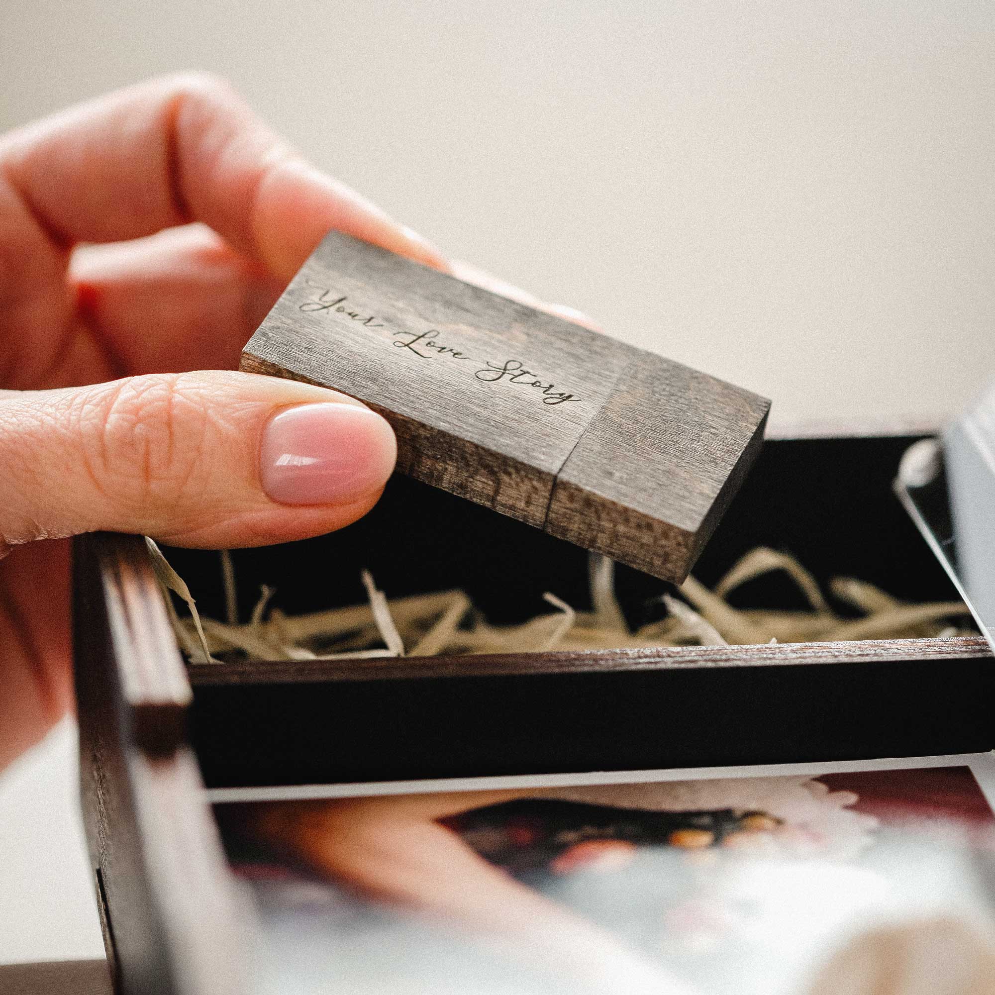 Close-up of engraved wooden USB flash drive inside black wedding photo box